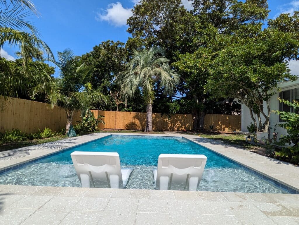 Custom inground pool built by pool builder Ponte Vedra Southern Elegance Pools, featuring a sun shelf and artistic pavers.