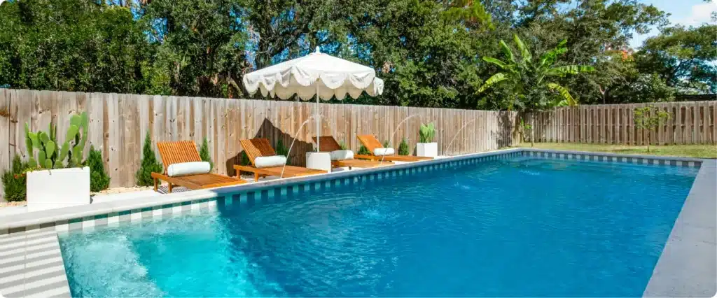Minimalist view of contemporary pool waterline tile, privacy fencing, and desert-inspired planter