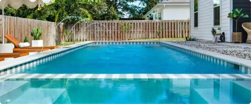 Contemporary rectangular pool with curved spa edge and striped two-tone tile detail near modern coastal home