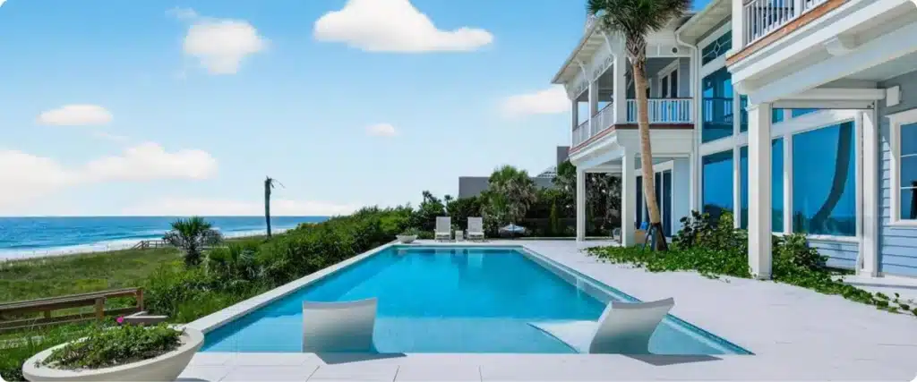 Side view of oceanfront pool and covered outdoor living space overlooking the shoreline