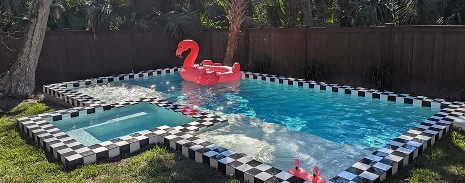Retro modern pool with custom black-and-white checkerboard coping, dual sun shelves, and integrated deck-level spa in Atlantic Beach backyard